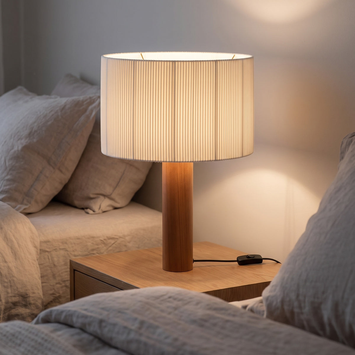Brisenne pleated table lamp lit on a bedside table