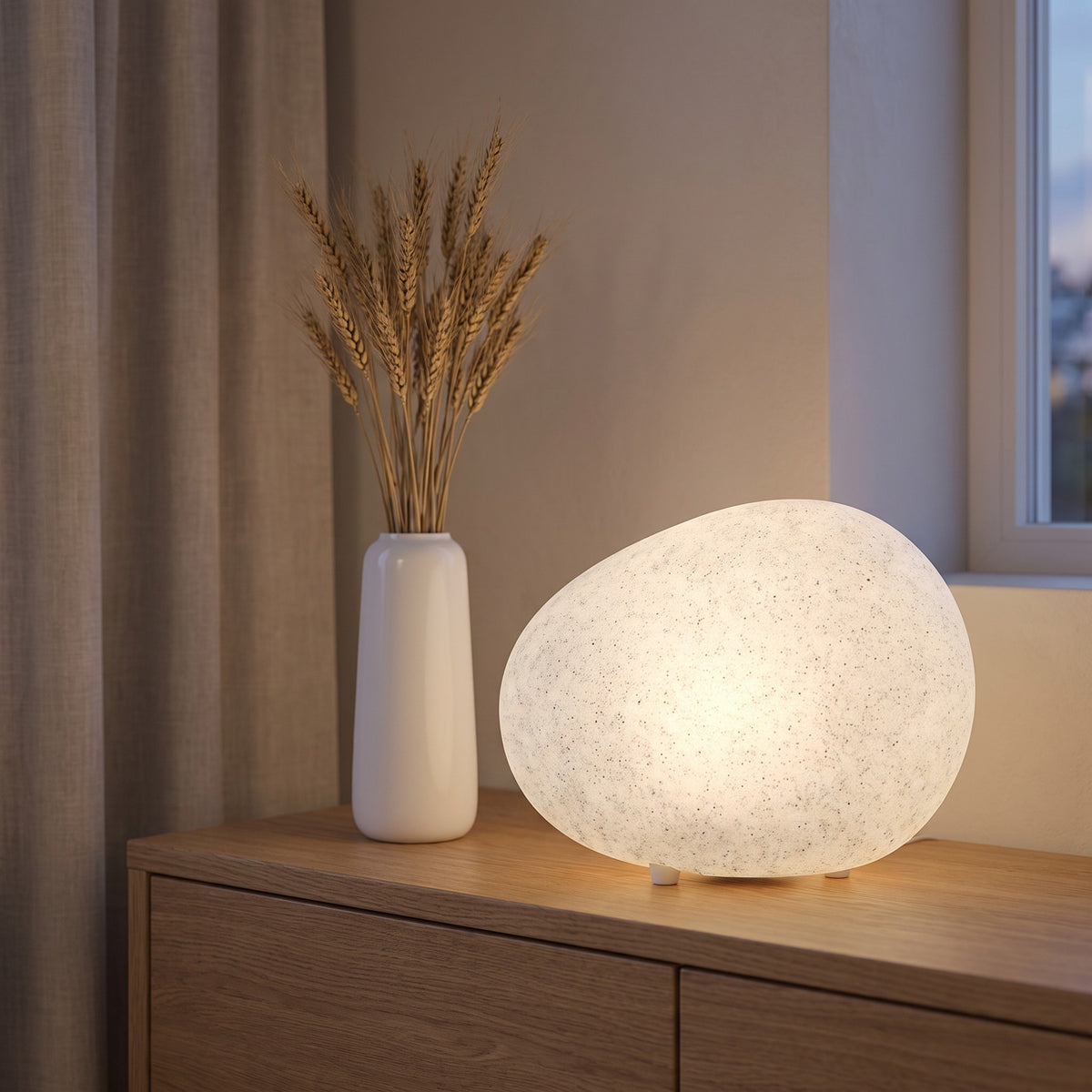 Lunara pebble lamp glowing on an oak sideboard