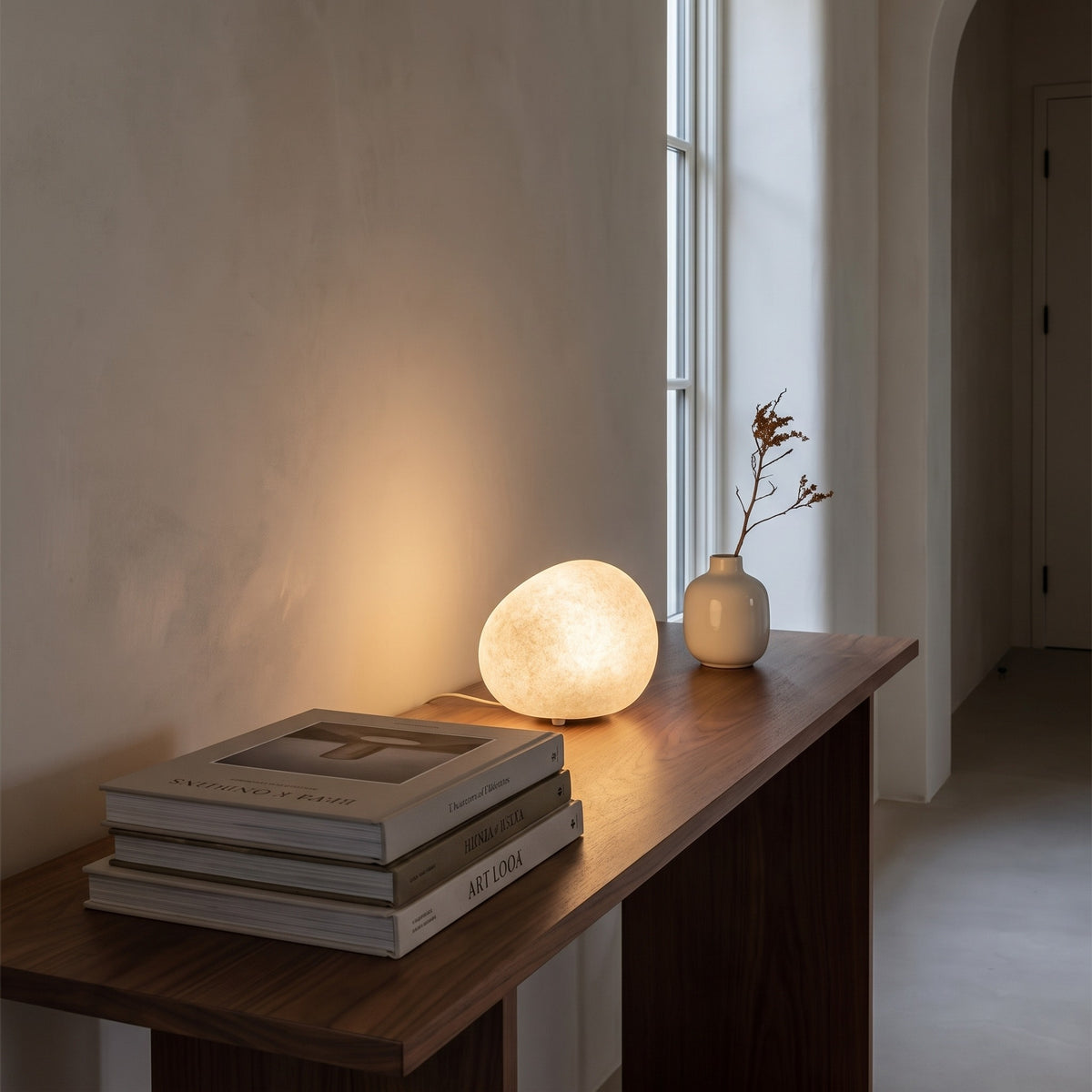 Lunara pebble table lamp glowing on a walnut hallway console