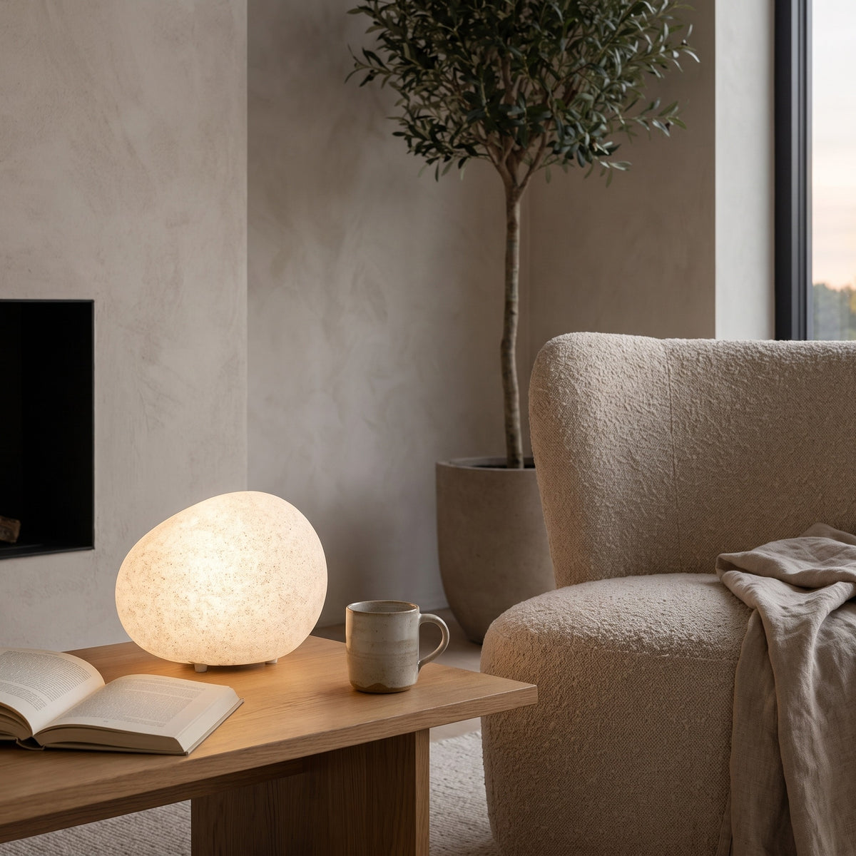 Lunara pebble lamp on an oak side table beside an armchair