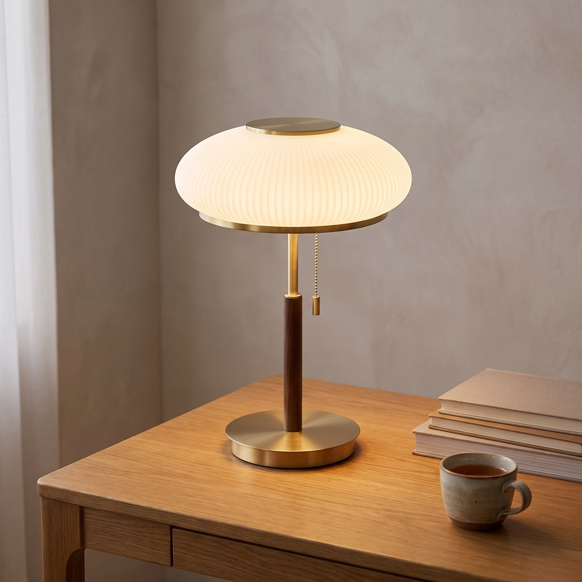 Maelis glass table lamp lit on an oak writing desk