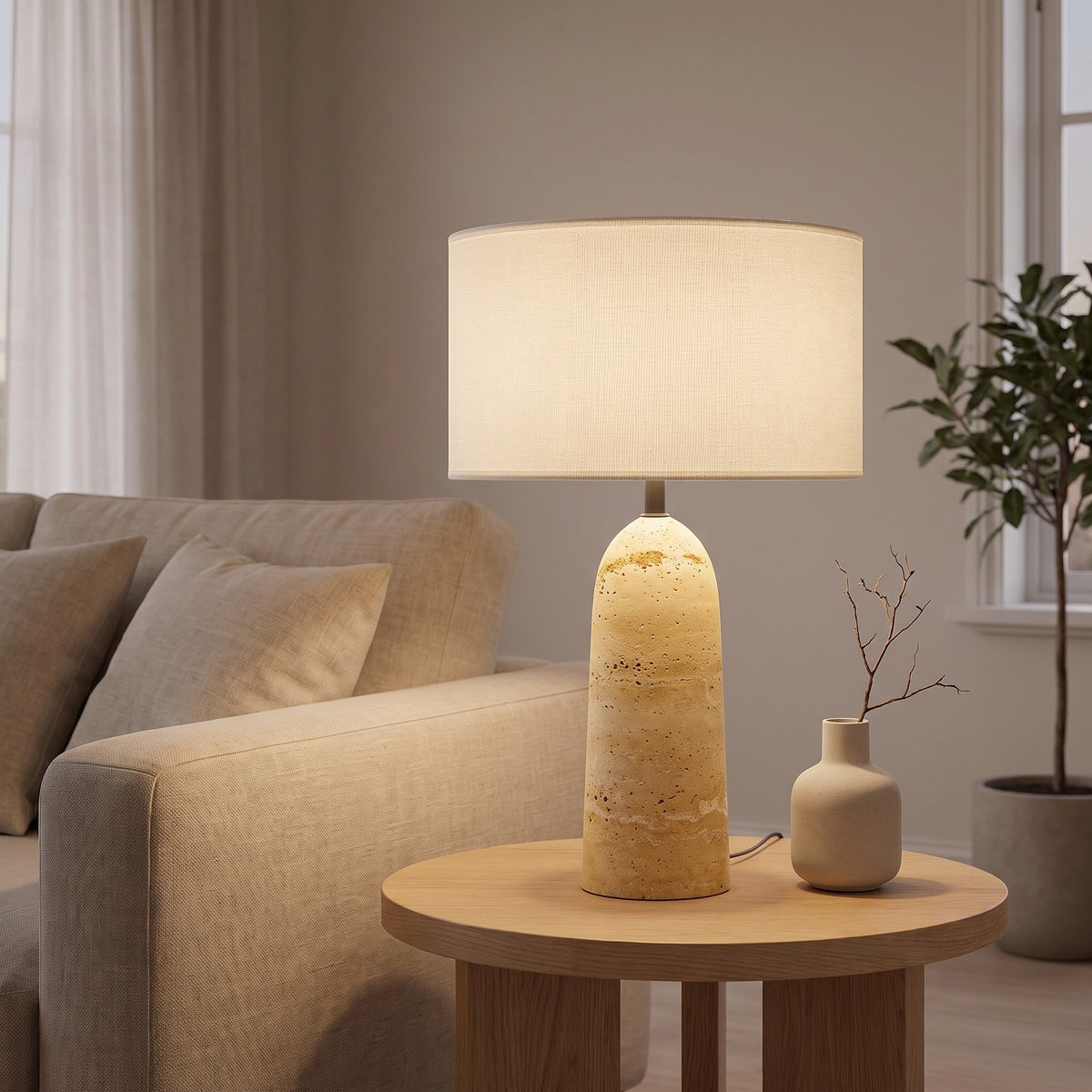 Ostara travertine lamp lit beside a linen sofa