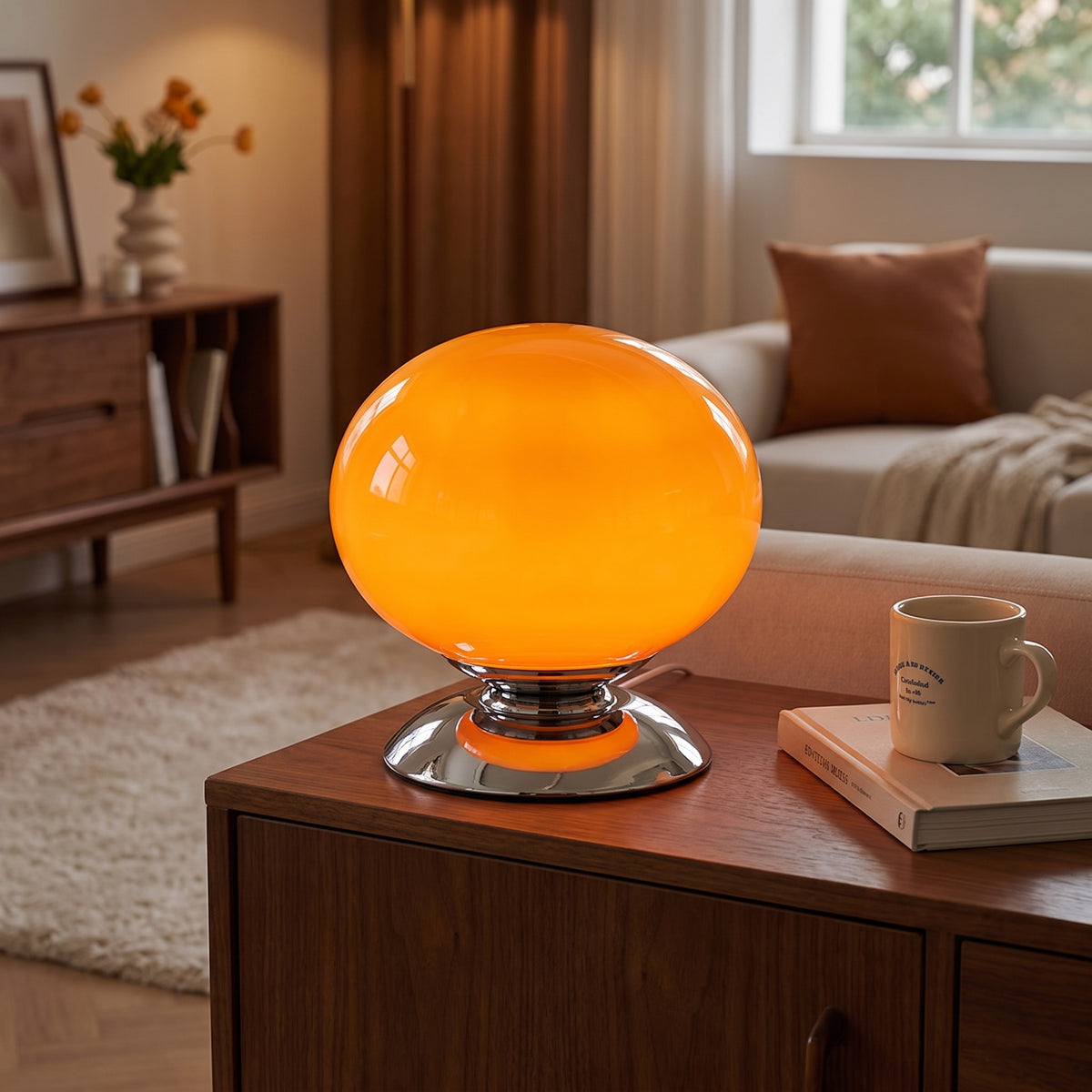 Tangerine Pastelle globe lamp lit on a walnut sideboard