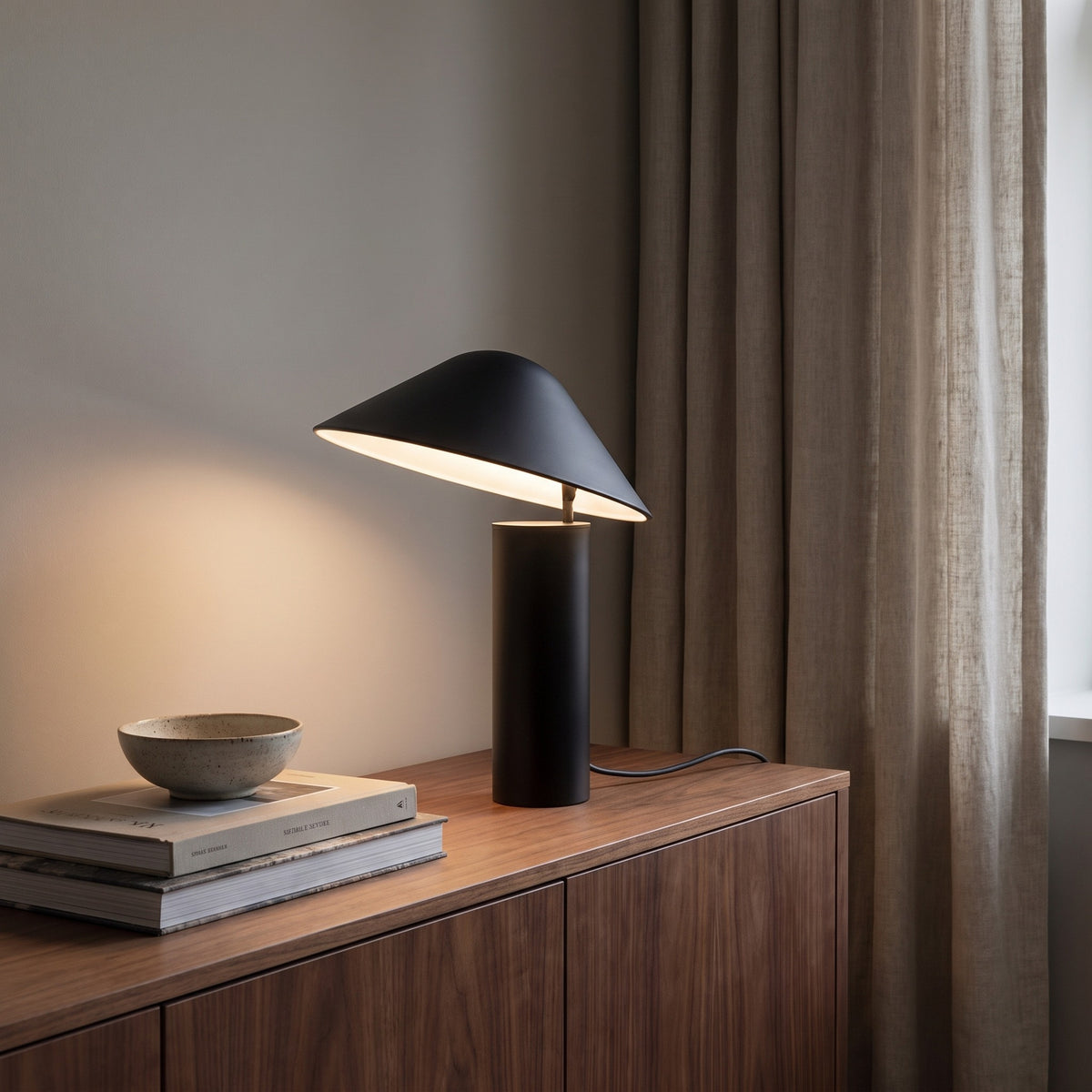Matte black Sorrelle table lamp lit on a walnut sideboard